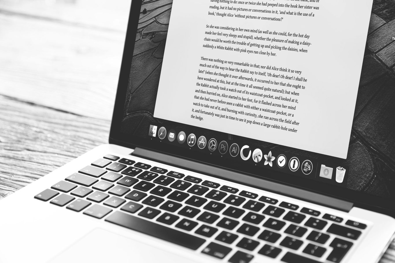 Junge Frau sitzt am Tisch mit Laptop, notiert etwas in ein Notizbuch.